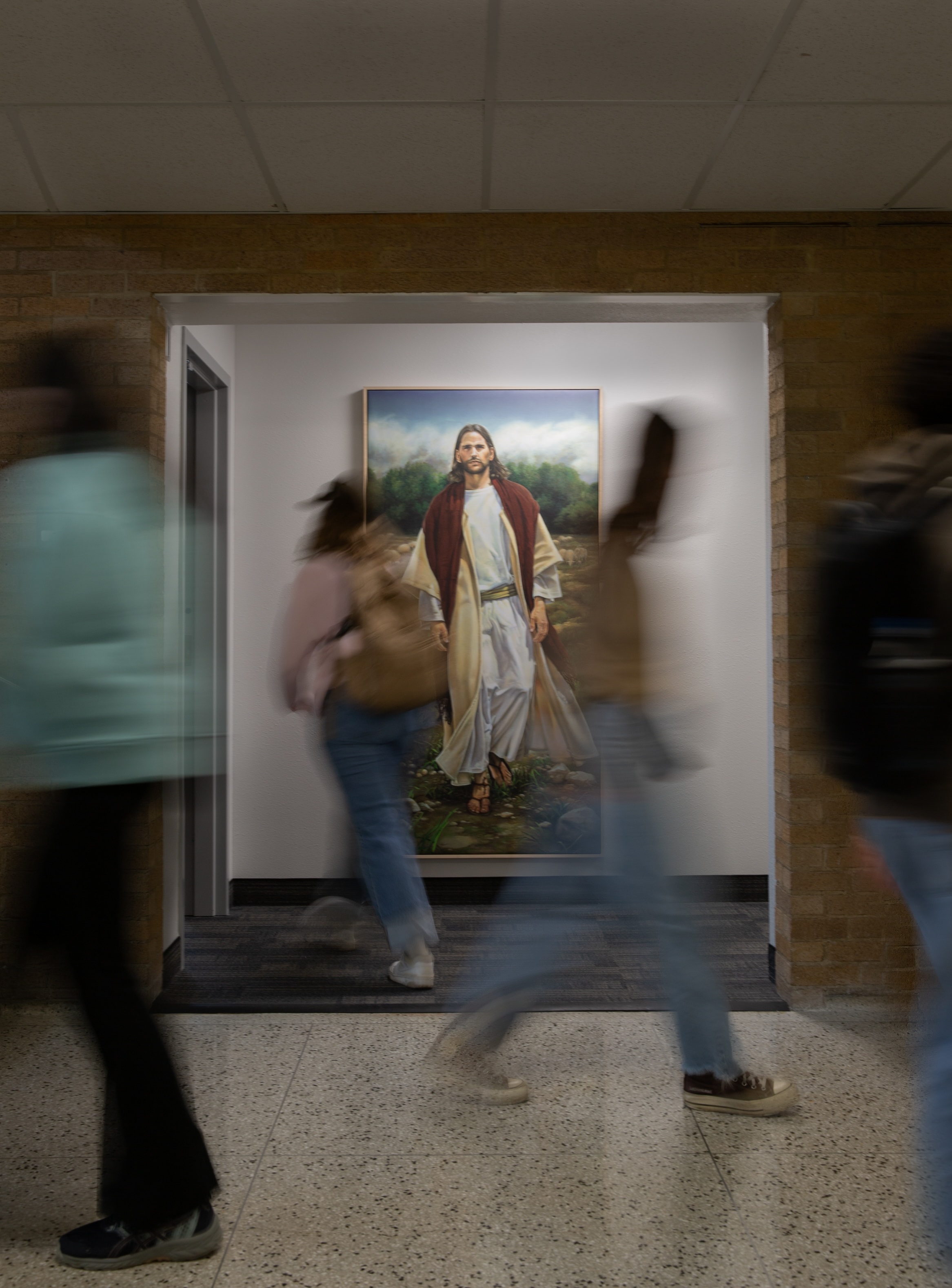 Blurr of students passing picture of Christ in the McKay Building