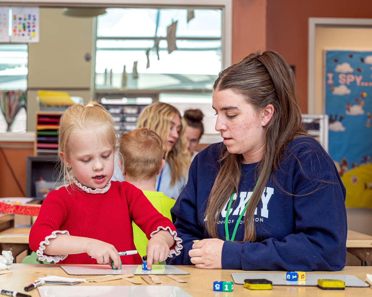 A female university student assists a young learner