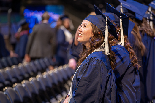 A BYU Graduate smiles in the Marriott Center at convocation