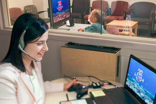 Woman with a headset smiling at a computer with a fish animation