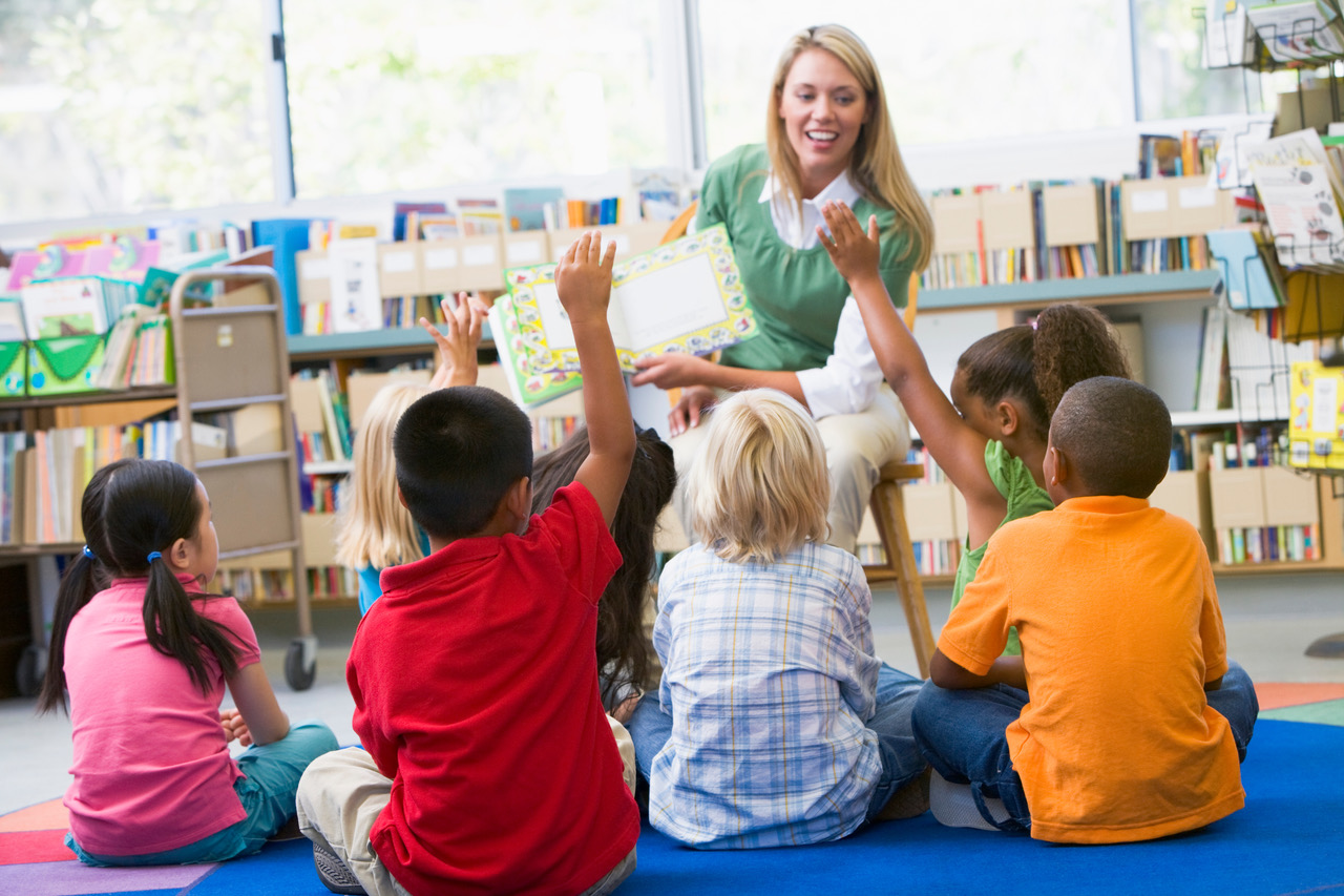 Lady reading to kids raising hands
