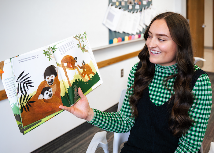 Girl reading a book to a classroom