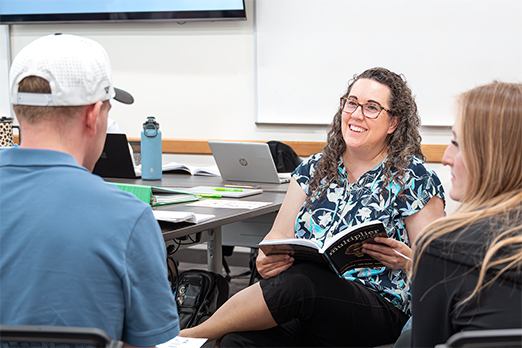 graduate students study a course textbook as a group