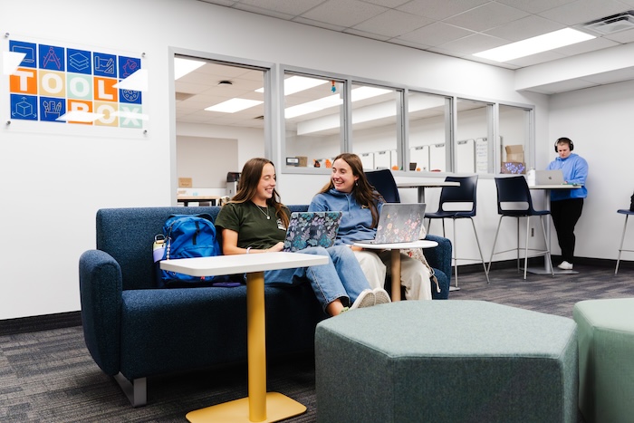 Two students sitting on couch, talking to each other