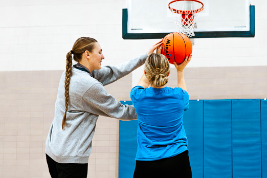 Girl learning to play basketball with her coach